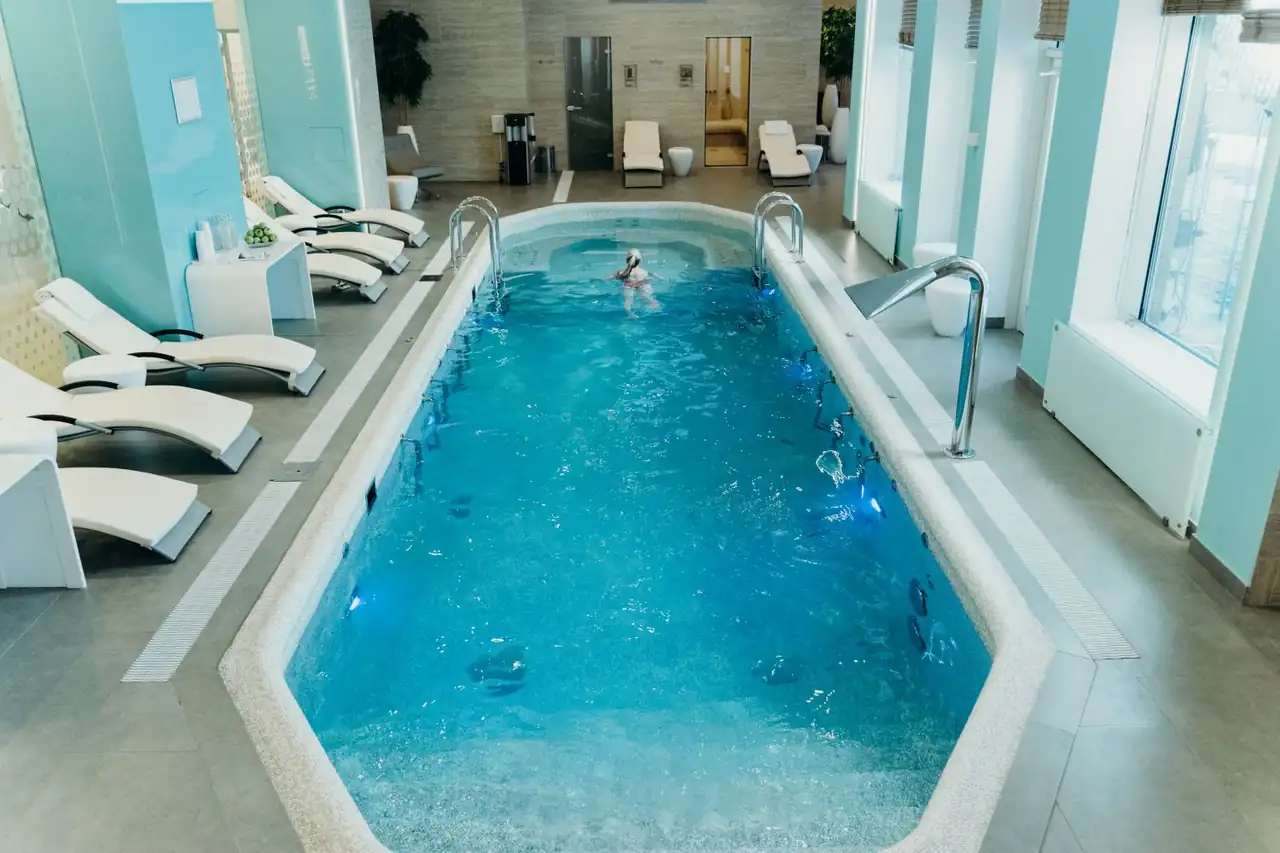 Bright indoor spa pool with lounge chairs and calm atmosphere.